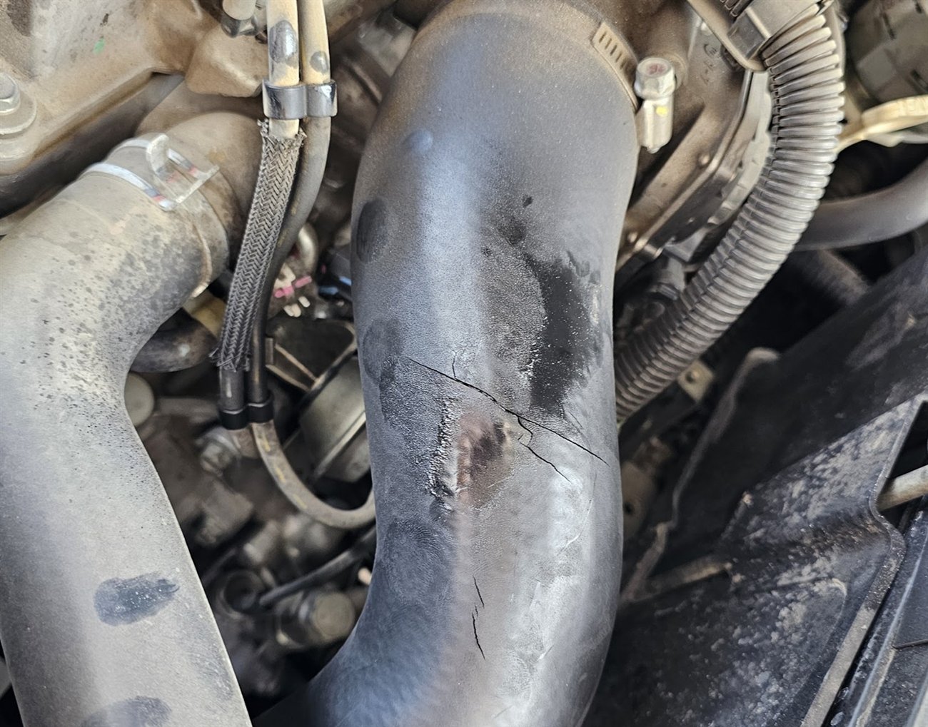 Manguito de refrigeración con una fisura longitudinal, fotografiado en el motor durante una diagnosis