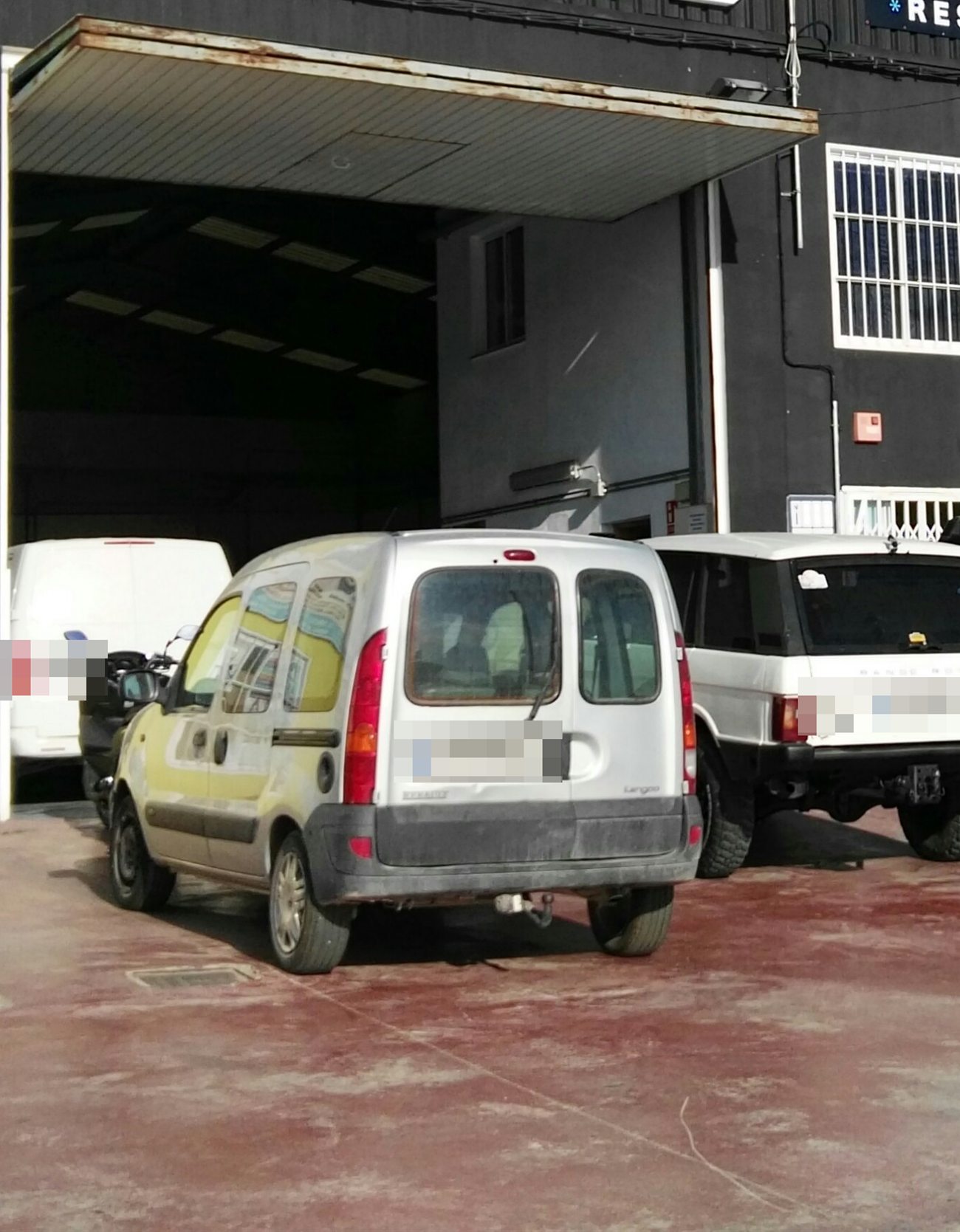 Portón de la nave de SGC Motorsport abierto, con vehículos esperando en el patio